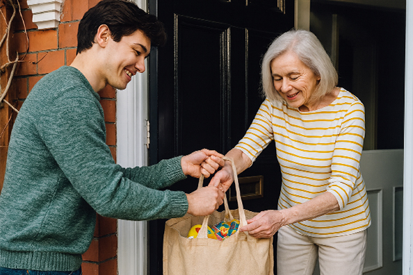 Delivery driver handing groceries to a lady on the front porch